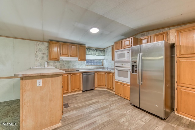 kitchen featuring lofted ceiling, stainless steel appliances, light countertops, under cabinet range hood, and light wood-type flooring