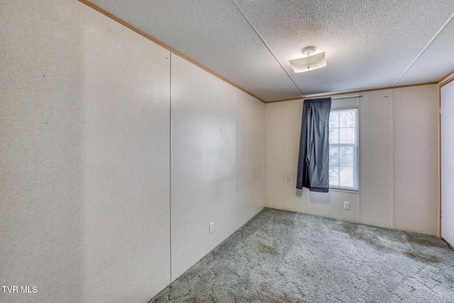 empty room featuring a textured ceiling, carpet flooring, and crown molding