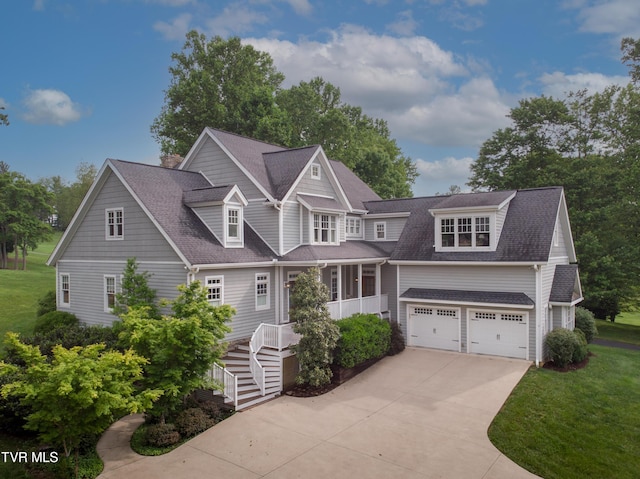 shingle-style home featuring a shingled roof, concrete driveway, stairs, a front yard, and a garage