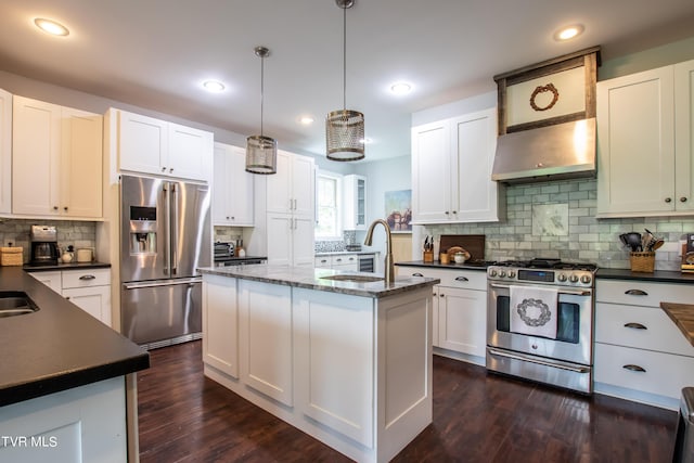 kitchen with a center island with sink, dark wood finished floors, a sink, under cabinet range hood, and appliances with stainless steel finishes