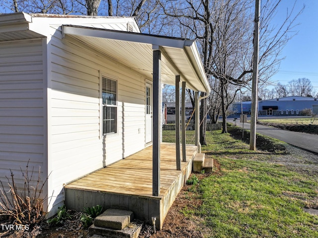 wooden terrace featuring a lawn and covered porch