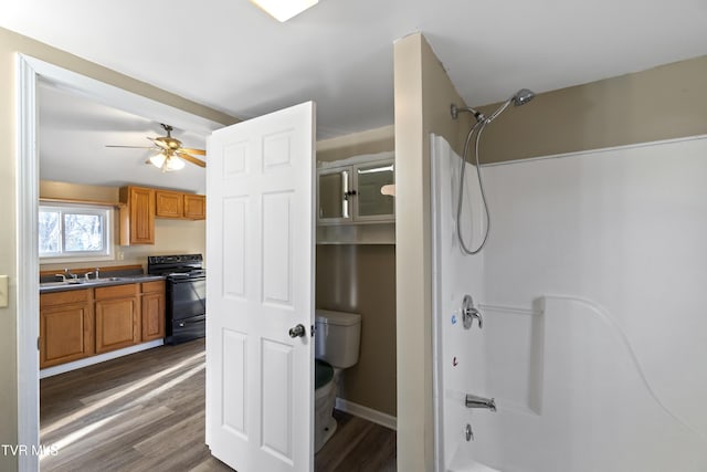 full bath featuring ceiling fan, shower / washtub combination, toilet, wood finished floors, and vanity