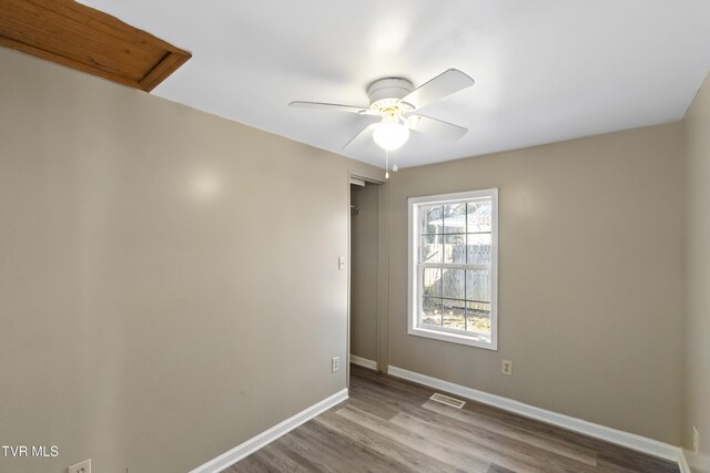 unfurnished room with ceiling fan, visible vents, baseboards, and wood finished floors