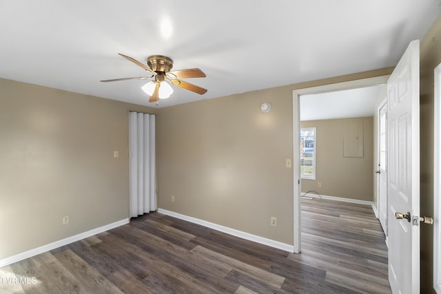 spare room with dark wood-style floors, a ceiling fan, and baseboards