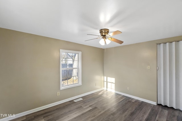 unfurnished room featuring dark wood-style floors, visible vents, a ceiling fan, and baseboards