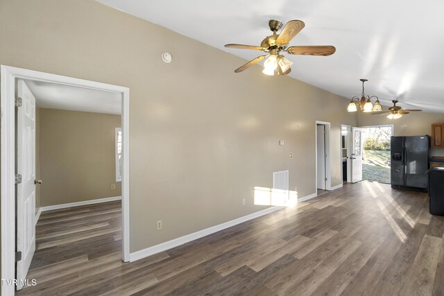 unfurnished living room featuring dark wood finished floors, lofted ceiling, ceiling fan with notable chandelier, and baseboards