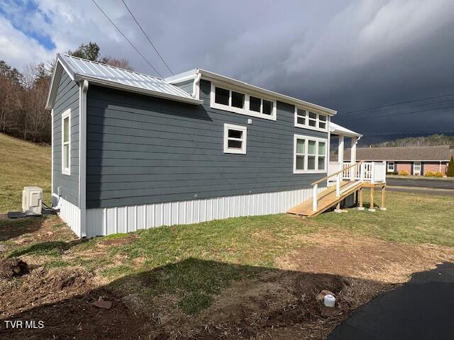 view of side of property with metal roof and a lawn