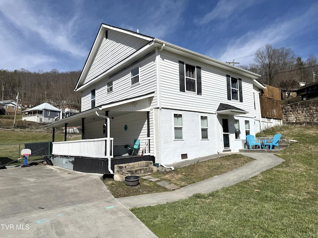 view of side of property with a yard, covered porch, and fence