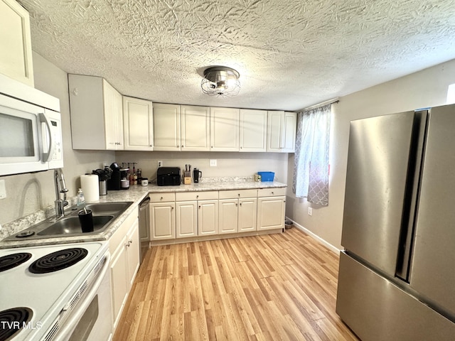 kitchen featuring light wood finished floors, stainless steel appliances, light countertops, white cabinets, and a textured ceiling