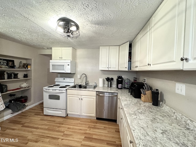 kitchen featuring white appliances, light wood finished floors, a sink, a textured ceiling, and white cabinetry