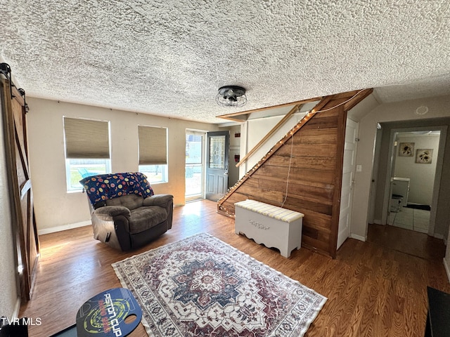 living room featuring stairway, baseboards, a textured ceiling, and wood finished floors