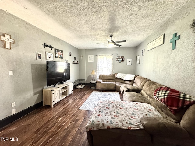 living room featuring a ceiling fan, baseboards, dark wood finished floors, a textured ceiling, and a textured wall