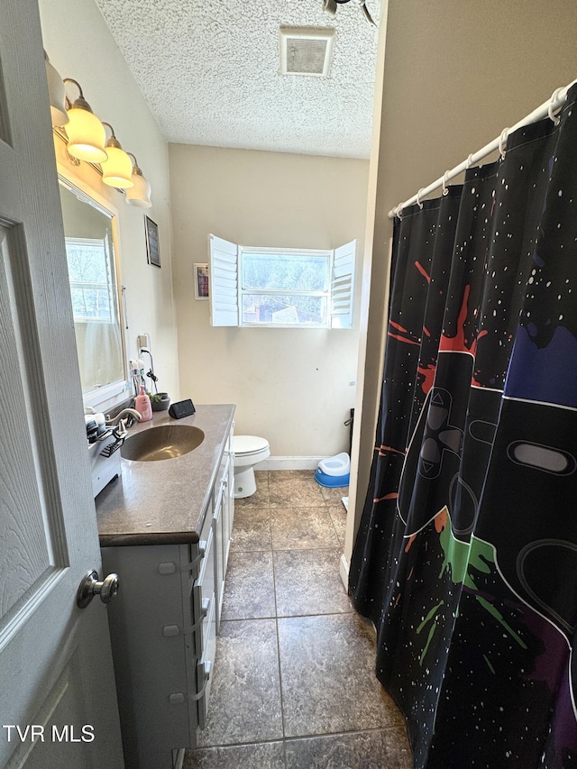 bathroom featuring visible vents, toilet, a textured ceiling, baseboards, and vanity