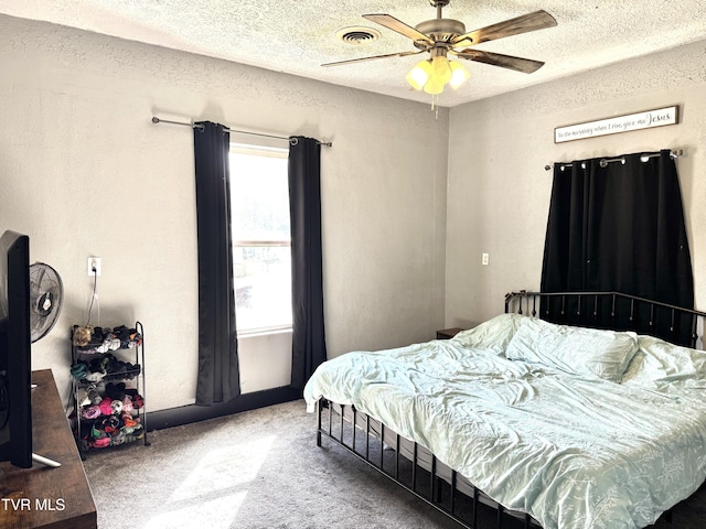 bedroom with a ceiling fan, visible vents, carpet floors, and a textured ceiling