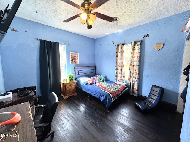 bedroom with visible vents, a ceiling fan, a textured ceiling, wood-type flooring, and a textured wall