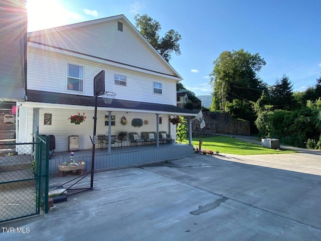 back of house featuring a patio, a lawn, a deck, and fence