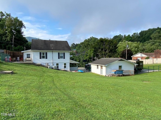 back of property with a lawn and fence