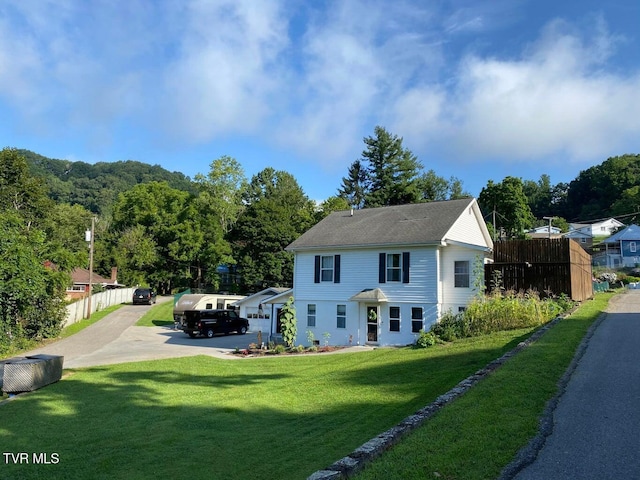 view of front of property featuring driveway, a front yard, and fence