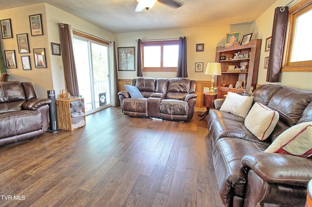 living room featuring dark wood finished floors, ceiling fan, and wainscoting