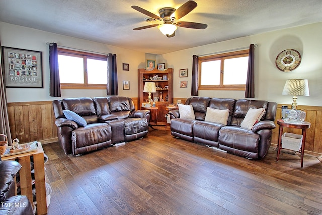 living area with a textured ceiling, dark wood-style flooring, and wainscoting