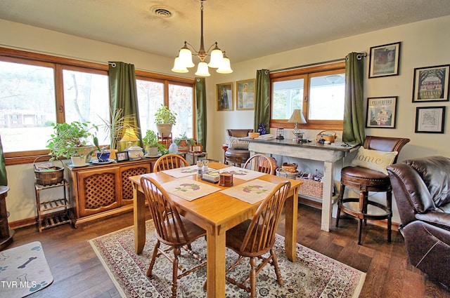 dining room featuring visible vents, a textured ceiling, an inviting chandelier, and wood-type flooring