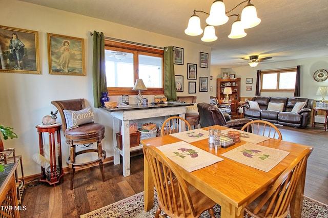 dining room with dark wood finished floors and ceiling fan with notable chandelier