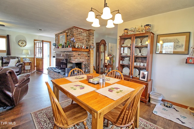 dining area with a notable chandelier, a fireplace, and dark wood-type flooring