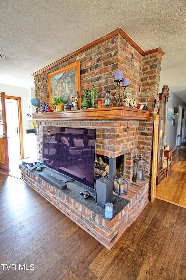 room details featuring visible vents, a brick fireplace, a textured ceiling, and wood finished floors