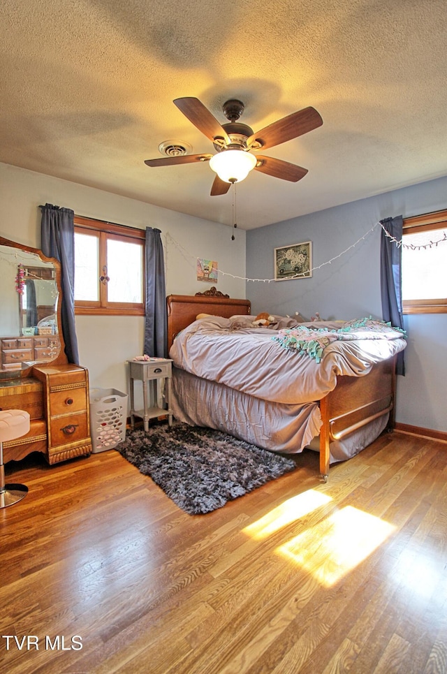 bedroom with a ceiling fan, wood finished floors, and a textured ceiling