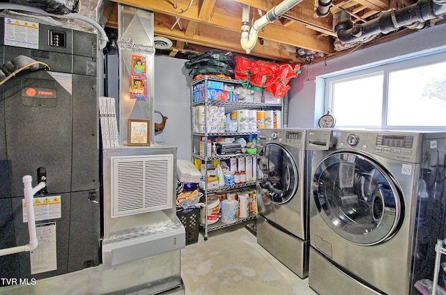 laundry room with heating unit, washing machine and dryer, and laundry area