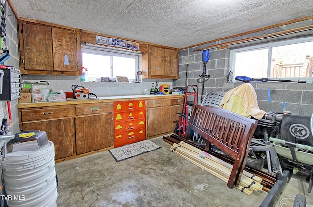 kitchen featuring brown cabinets, concrete floors, and concrete block wall