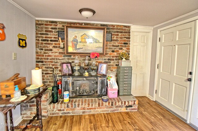 living area with brick wall, wood finished floors, and crown molding