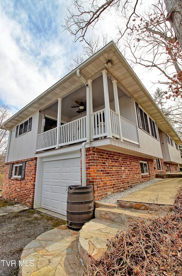 view of home's exterior with a garage, driveway, brick siding, and a ceiling fan