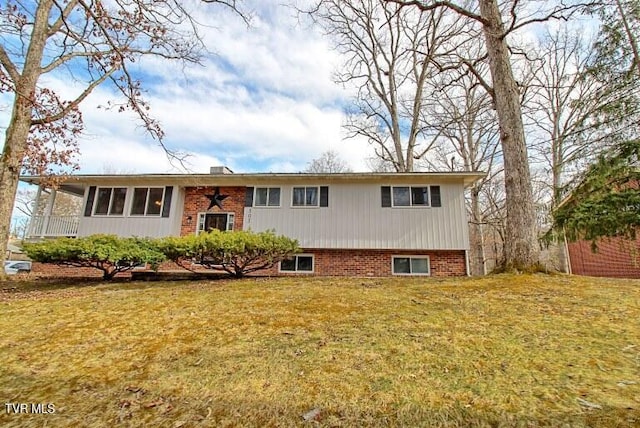 raised ranch with brick siding and a front yard