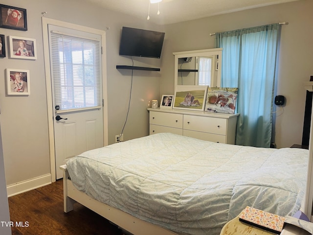 bedroom featuring baseboards and dark wood-style flooring