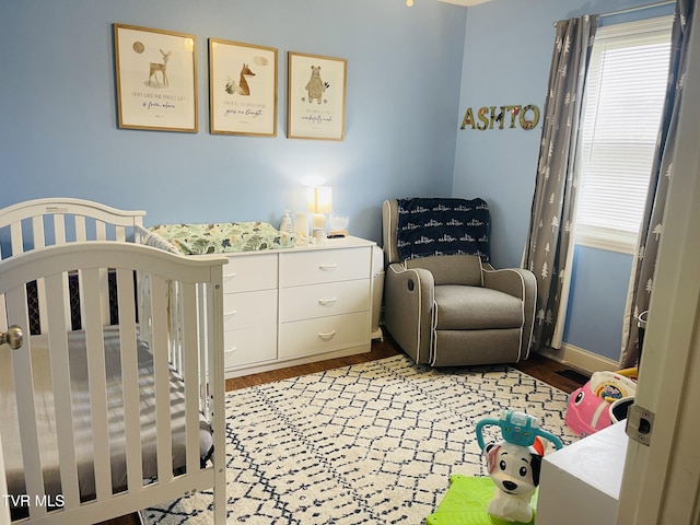 bedroom featuring a nursery area and wood finished floors