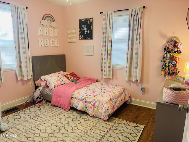 bedroom featuring wood finished floors, visible vents, and baseboards