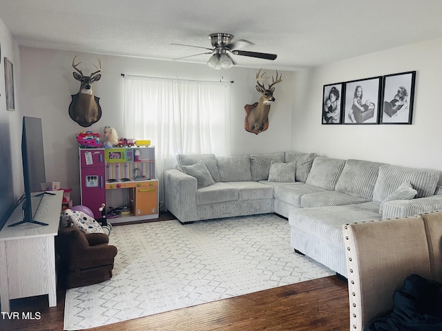 living room with a ceiling fan, wood finished floors, and a textured ceiling