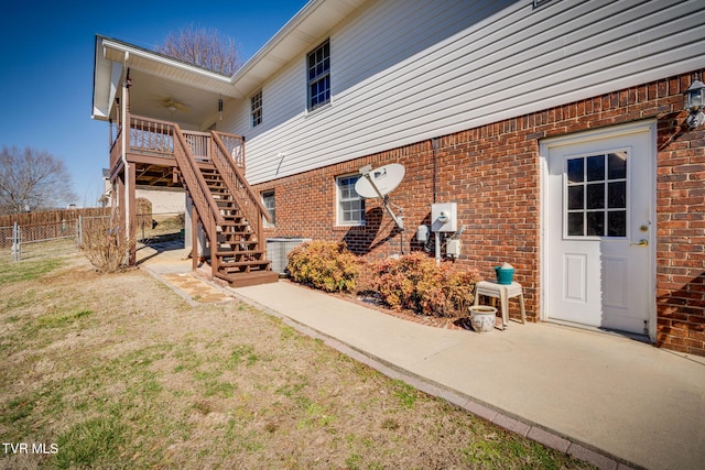 back of property with stairs, fence, a ceiling fan, and brick siding