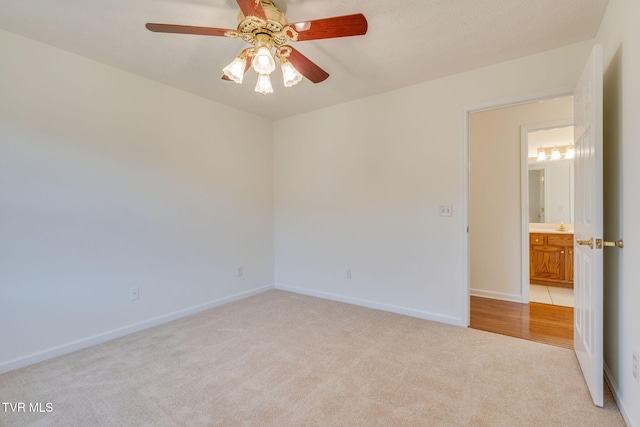 empty room featuring baseboards, light colored carpet, and a ceiling fan