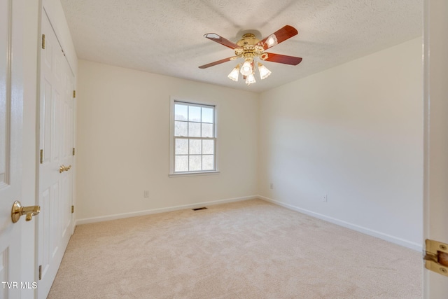 carpeted spare room featuring visible vents, baseboards, a textured ceiling, and a ceiling fan