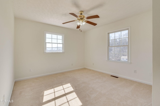 carpeted empty room featuring ceiling fan, baseboards, visible vents, and a textured ceiling