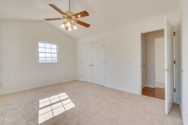 unfurnished bedroom featuring light carpet, baseboards, lofted ceiling, and a closet