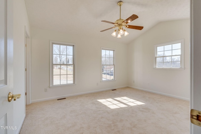 spare room with carpet flooring, baseboards, visible vents, and vaulted ceiling