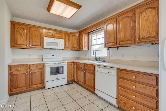 kitchen with a sink, white appliances, and brown cabinets