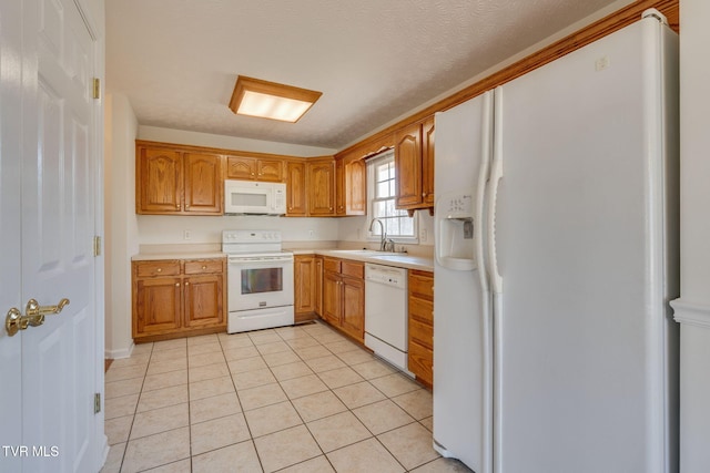 kitchen featuring light tile patterned flooring, white appliances, light countertops, and a sink