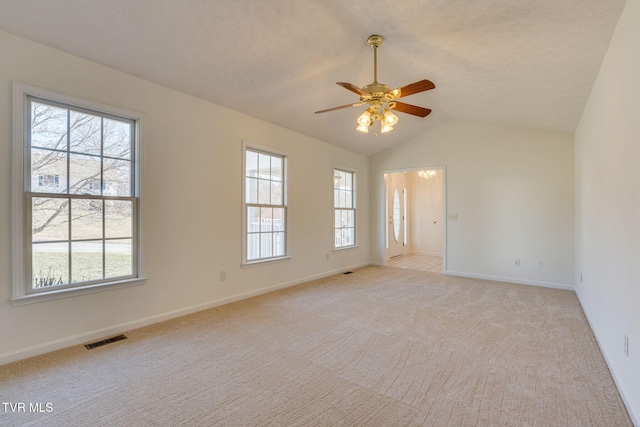 spare room with visible vents, light colored carpet, a healthy amount of sunlight, and vaulted ceiling