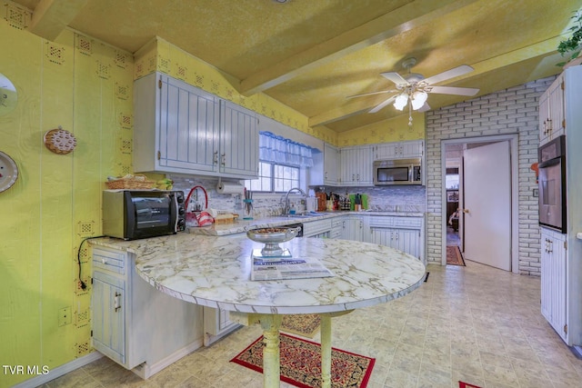 kitchen with black appliances, a ceiling fan, a sink, tasteful backsplash, and a peninsula