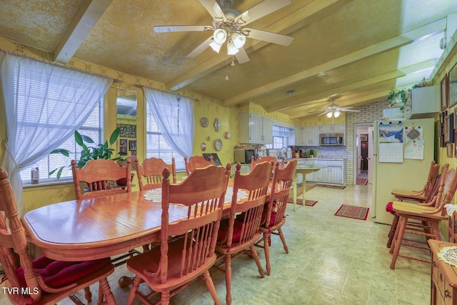 dining space with beamed ceiling, plenty of natural light, light floors, and ceiling fan