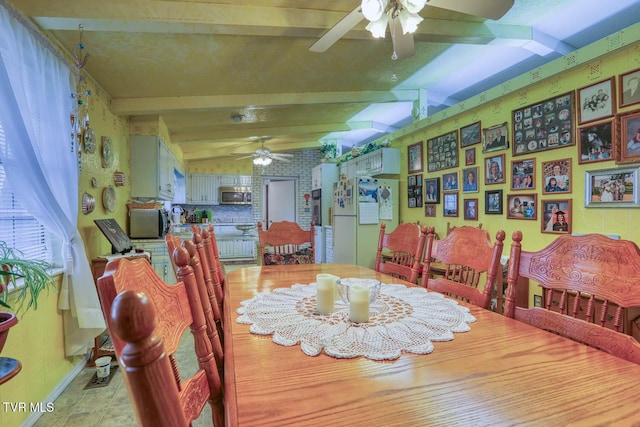 dining area featuring baseboards, lofted ceiling with beams, and a ceiling fan